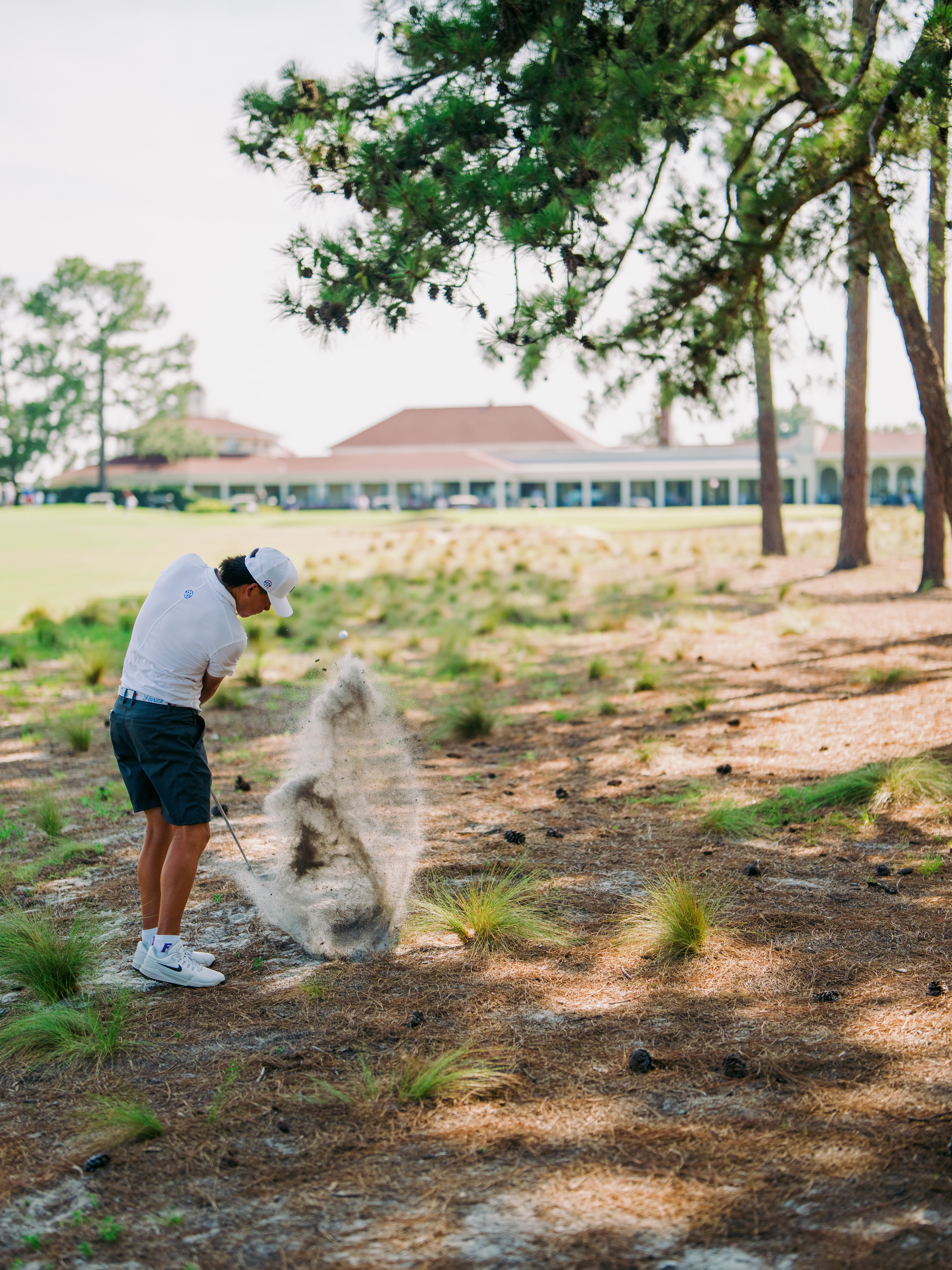 Joshua Bai plays from under the trees into the 18th green on his way to victory.
